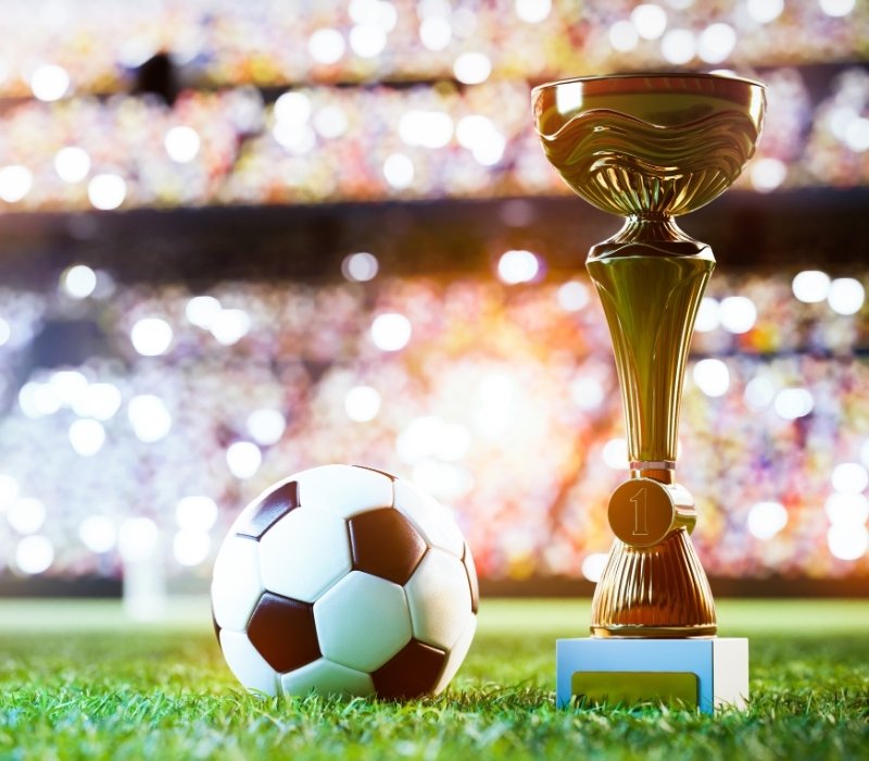 soccer ball and trophy cup on a stadium field