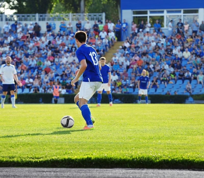 Soccer player controlling the ball in a packed stadium on a sunny day