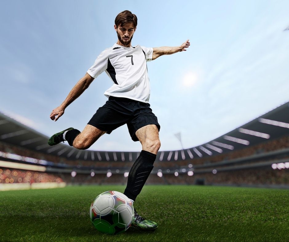 Soccer player striking the ball on a green football field