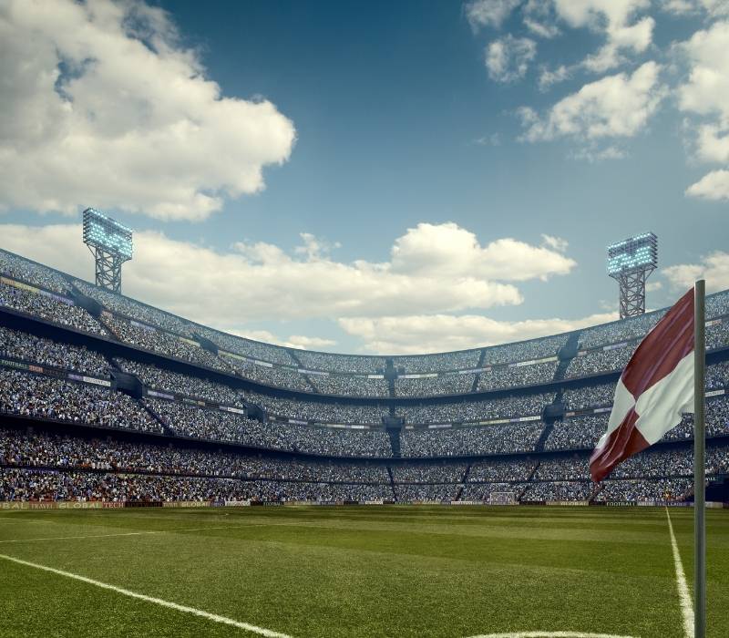 Sunny football stadium filled with spectators and green soccer pitch